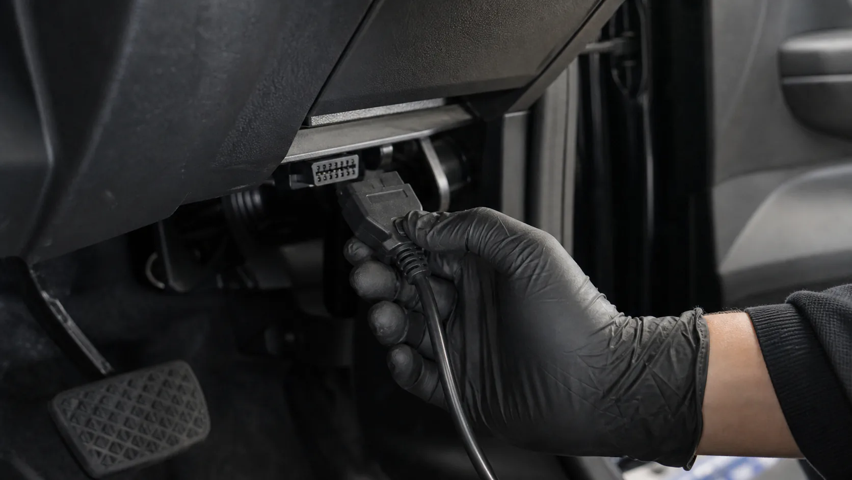 Araç içindeki OBD2 soketine diagnostik bağlantı kablosu takan servis teknisyeni